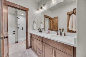 Bathroom featuring double vanity, tile patterned floors, a stall shower, and a sink