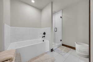 Bathroom featuring tile patterned flooring, a shower stall, a bath, and baseboards
