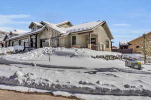 View of front of house featuring stone siding, board and batten siding, an attached garage, and fence