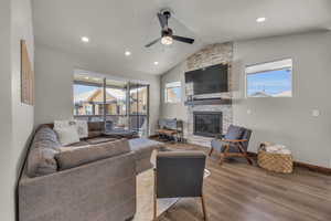 Living room featuring wood finished floors, baseboards, lofted ceiling, recessed lighting, and a stone fireplace