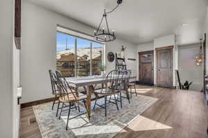 Dining room with a chandelier, baseboards, visible vents, and wood finished floors