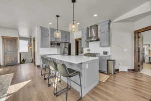 Kitchen featuring gray cabinets, appliances with stainless steel finishes, light countertops, and wall chimney exhaust hood