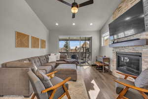 Living area with lofted ceiling, a healthy amount of sunlight, wood finished floors, and a fireplace