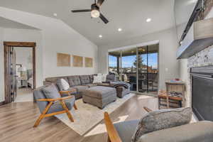 Living area with a ceiling fan, light wood-style flooring, recessed lighting, a fireplace, and vaulted ceiling