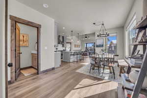 Dining area with a notable chandelier, recessed lighting, baseboards, and light wood-style floors