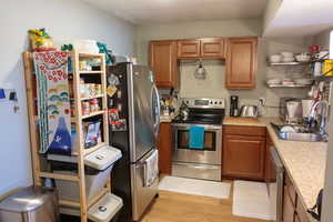 Kitchen with a sink, stainless steel appliances, granite countertops, laminate floors, and brown cabinets