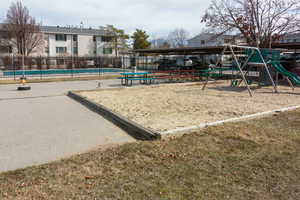 View of community featuring a swimming pool, fence, and playground community