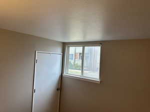 Unfurnished bedroom with a textured wall, a closet, and a textured ceiling