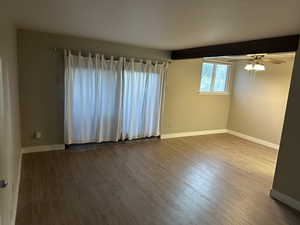 Spare room with dark wood-style floors, a ceiling fan, and beam ceiling