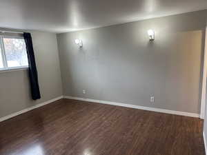 Unfurnished room featuring dark wood-style floors and baseboards