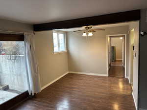 Empty room with beam ceiling, ceiling fan, baseboards, and wood finished floors