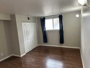 Unfurnished bedroom featuring visible vents, baseboards, a closet, and wood finished floors