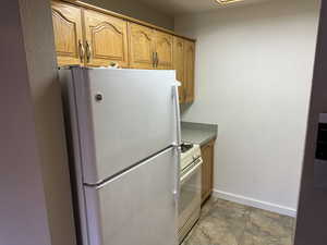 Kitchen featuring brown cabinets, white appliances, and baseboards