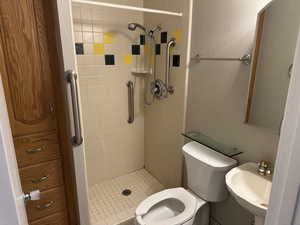 Full bathroom with a sink, toilet, a stall shower, and a textured wall