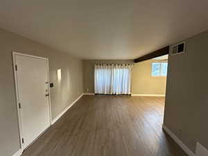 Unfurnished living room with dark wood-type flooring and baseboards