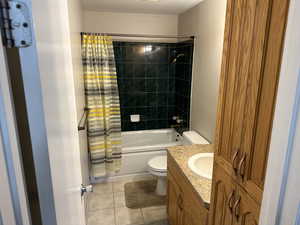 Full bath featuring tile patterned flooring, toilet, vanity, and shower / bathtub combination with curtain