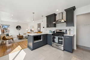 Kitchen area with stainless appliance and gas stove with stainless vent hood.