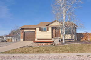 Ranch-style house with fence, an attached garage, a shingled roof, concrete driveway, and brick siding