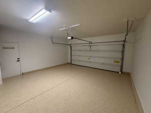 Garage featuring a garage door opener and baseboards