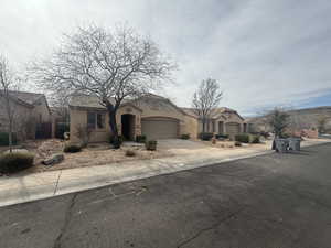 View of front of house with fence, a garage, driveway, and stucco siding