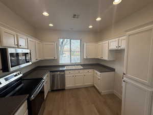 Kitchen with visible vents, a sink, white cabinets, appliances with stainless steel finishes, and dark countertops