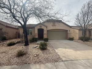 Mediterranean / spanish-style house with stucco siding, stone siding, a garage, and concrete driveway