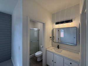 Full bathroom featuring a stall shower, toilet, vanity, and wood finished floors