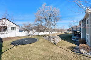View of yard featuring stairs, a trampoline, and a fenced backyard