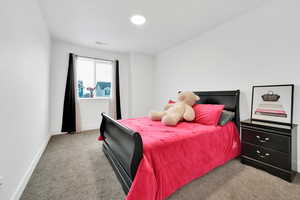 Carpeted bedroom featuring visible vents and baseboards