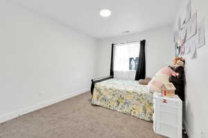 Carpeted bedroom featuring visible vents and baseboards