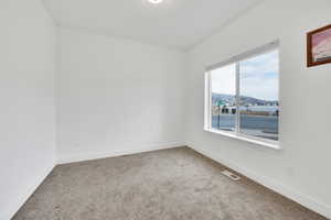Carpeted empty room featuring visible vents, baseboards, and a mountain view