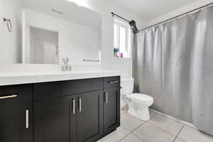 Full bath featuring tile patterned flooring, toilet, vanity, and visible vents