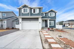 View of front of house featuring concrete driveway, an attached garage, and fence