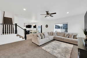 Carpeted living area featuring stairway, recessed lighting, baseboards, and ceiling fan
