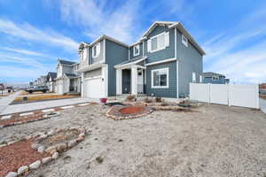 View of front facade with driveway, an attached garage, and fence