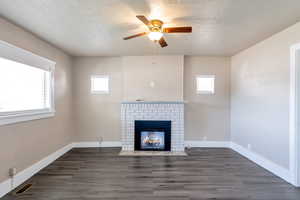 Unfurnished living room with visible vents, baseboards, wood finished floors, and a fireplace