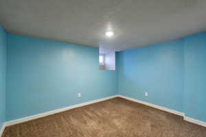 Interior space with baseboards, a textured ceiling, and dark carpet