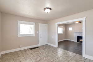 Foyer with visible vents, a brick fireplace, a textured ceiling, and baseboards