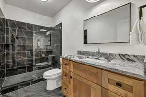 Full bathroom with a walk in shower, toilet, vanity, tile patterned floors, and a textured ceiling