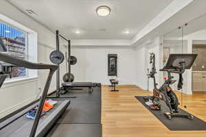 Exercise area with visible vents, baseboards, plenty of natural light, and wood finished floors
