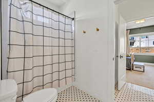 Ensuite bathroom with connected bathroom, toilet, a shower with shower curtain, and baseboards