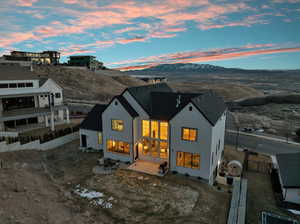 Back of house at dusk with fence, a mountain view, and stucco siding