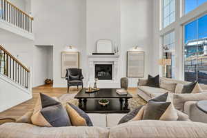 Living room with a glass covered fireplace, stairs, baseboards, and wood finished floors