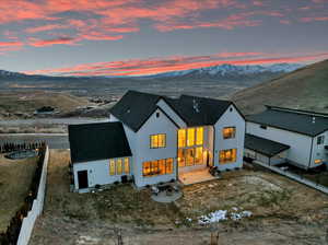 Back of property at dusk with a mountain view, stucco siding, and fence
