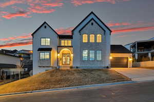 View of front of property featuring french doors, fence, stone siding, and driveway