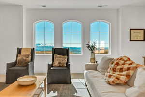 Living area with a wealth of natural light, visible vents, and carpet flooring