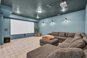 Carpeted home theater featuring visible vents, baseboards, and a textured ceiling