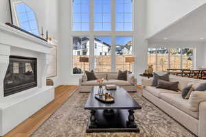 Living area featuring a glass covered fireplace, a high ceiling, wood finished floors, and baseboards