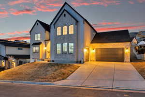 View of front of property featuring stone siding, stucco siding, concrete driveway, and a garage
