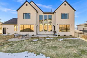 Rear view of property featuring stucco siding, a patio, and fence